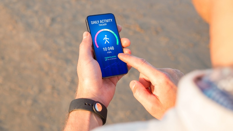 Main d'homme tenant un smartphone affichant une application de suivi d'activité physique